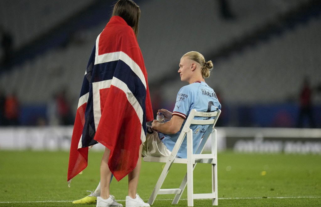 Erling Haland sedi na stolici i razgovara sa navijačicom ogrnutom u zastavu Norveške